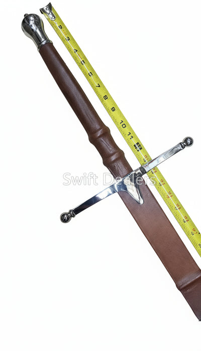 Sword with brown sheath and silver blade on a wooden surface, measured by a tape measure.